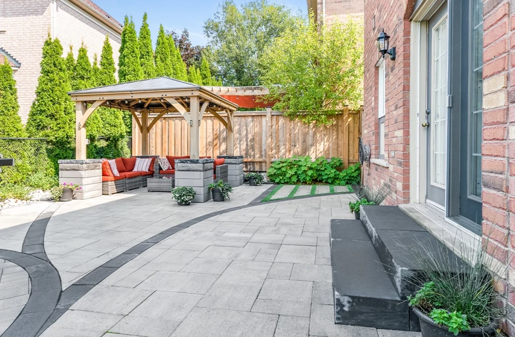 Backyard interlock paver patio floor with a wooden gazebo