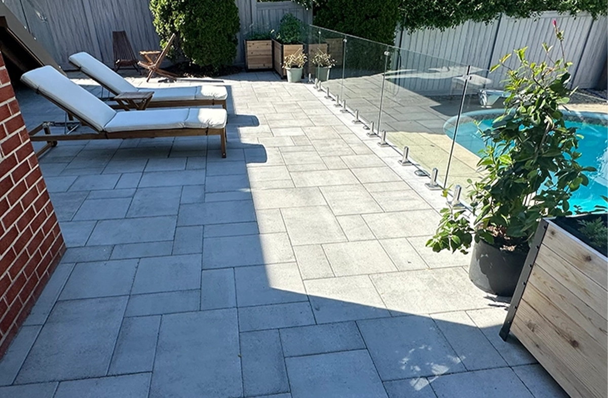 Premium interlocking patio with glass railing beside a backyard pool